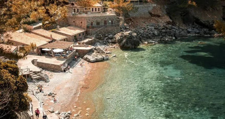 Cala de Deià con aguas cristalinas y acantilados de roca en Mallorca