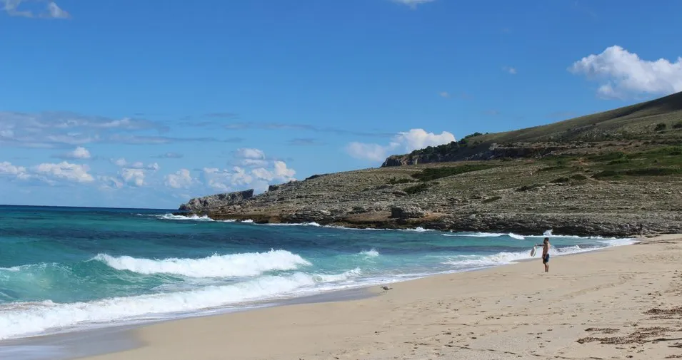 Bañistas en la playa de Cala Mesquida con aguas turquesas en el este de Mallorca
